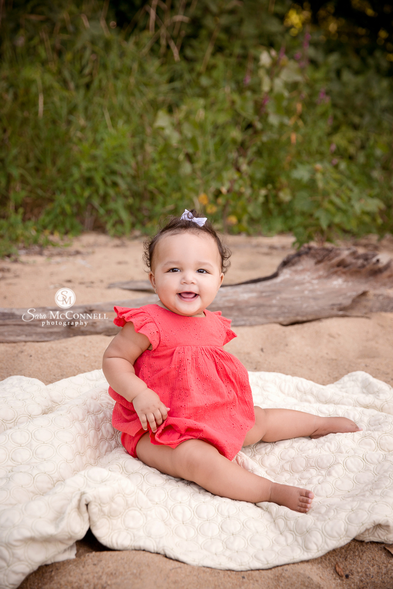 Baby smiling while sitting on a blanket on the beach