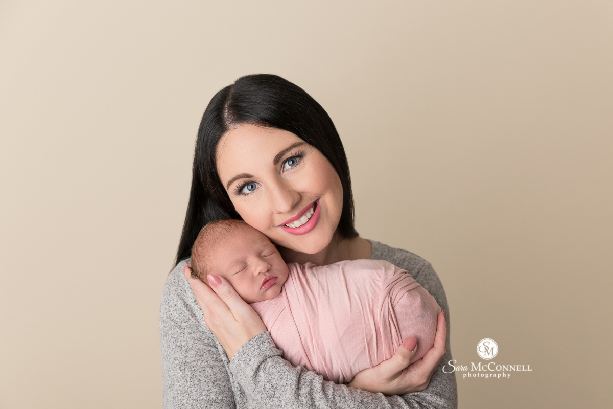 Mother holding her newborn baby during a newborn photo session with Sara McConnell Photography