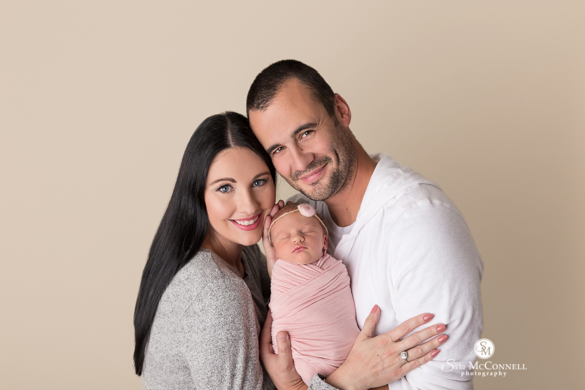 Mother and father holding their newborn baby during a newborn photo session with Sara McConnell Photography