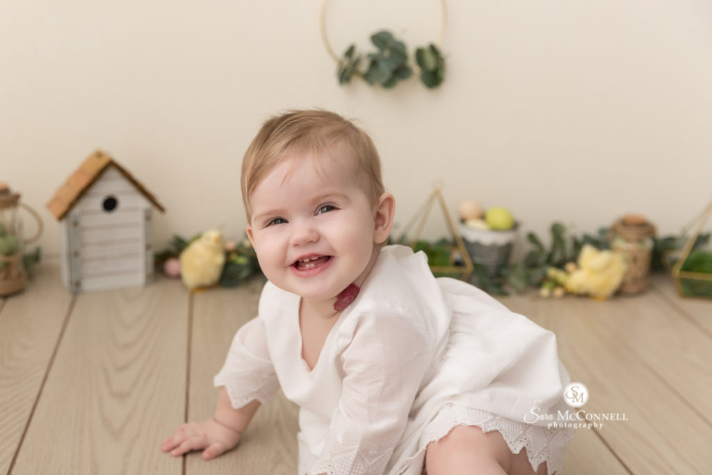 baby smiling in front of greenery and spring decor