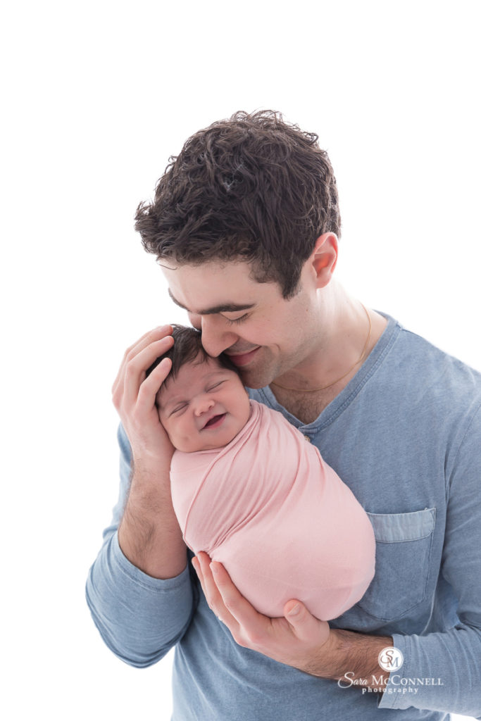 dad holding newborn baby wrapped in pink