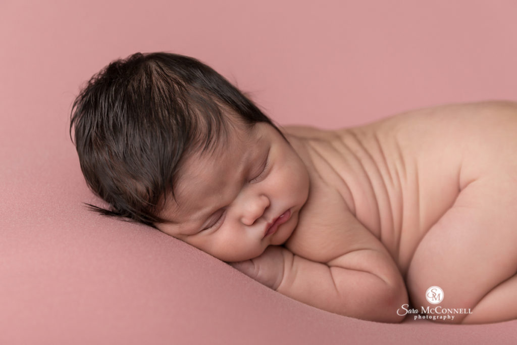 newborn baby sleeping on pink 