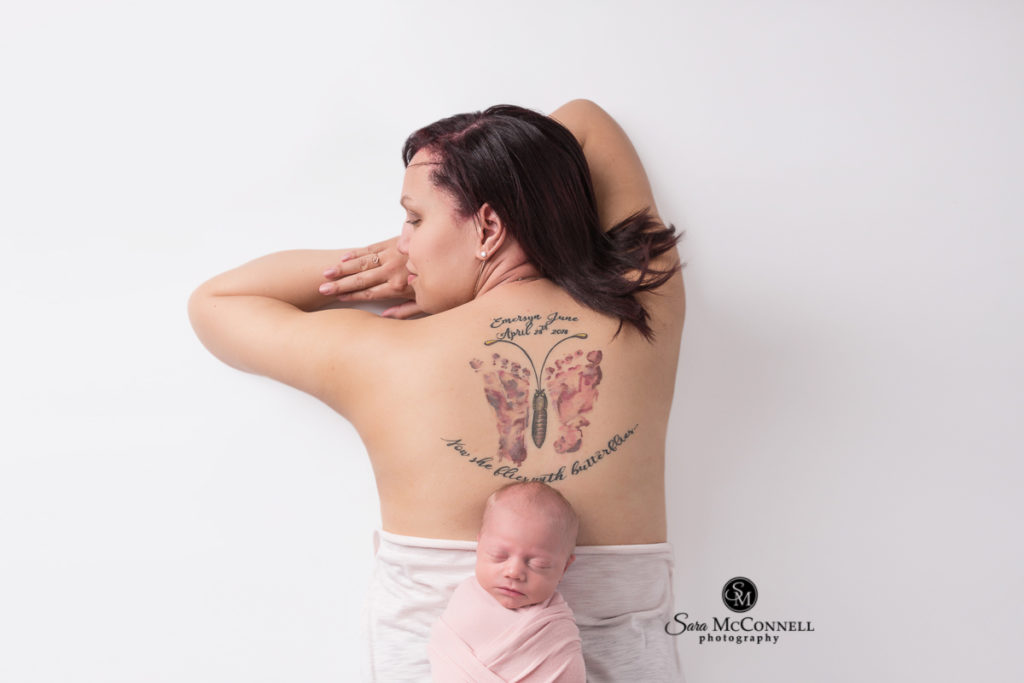newborn baby sleeping on mother's back with butterfly tattoo