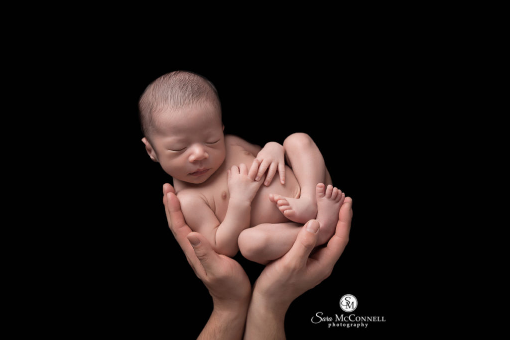 newborn baby being held in a pair of hands