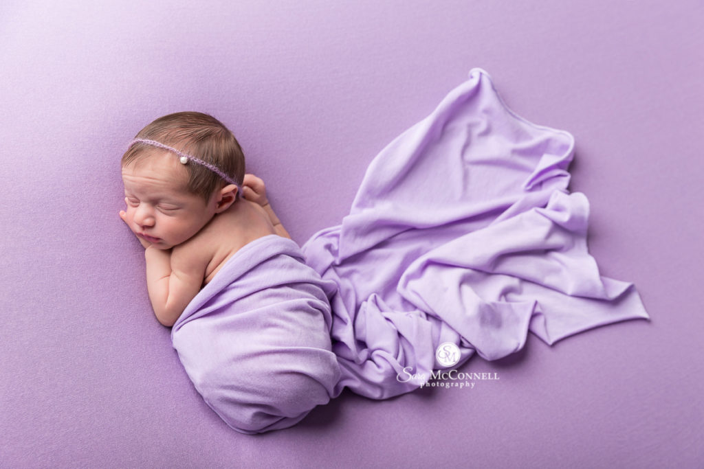 sleeping newborn baby wrapped in purple