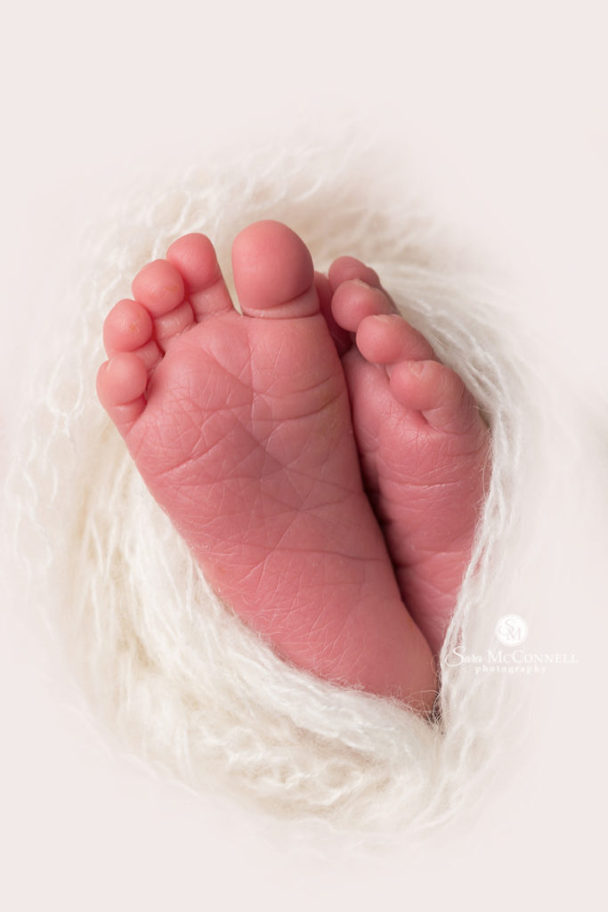 close up of newborn baby toes in white blanket