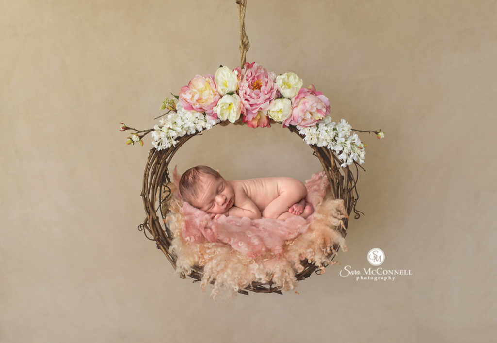 newborn sleeping in a wreath of flowers