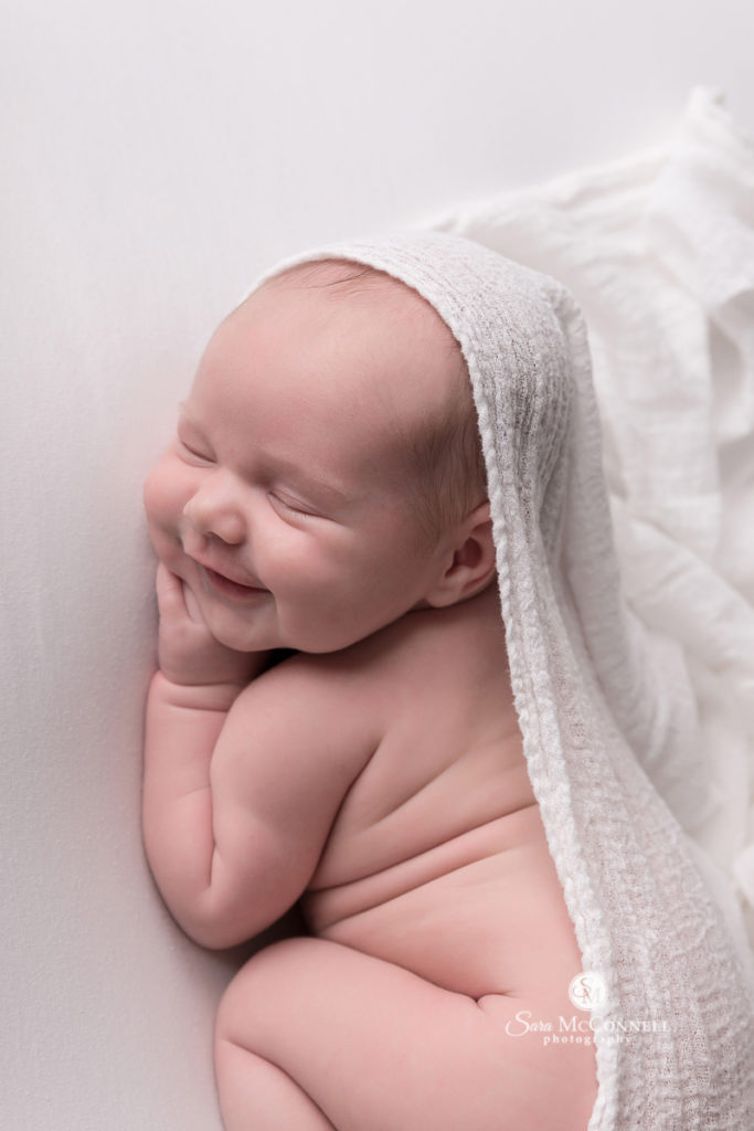smirking newborn baby with white cloth