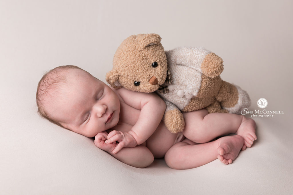 sleeping newborn baby with a teddy bear