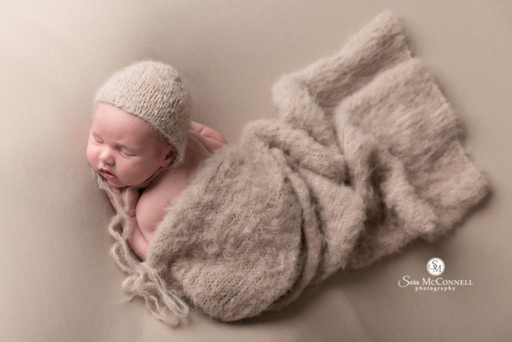 newborn baby sleeping with knit hat and blanket