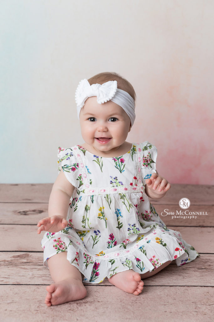 8 month old baby in a flower dress wearing a white headband