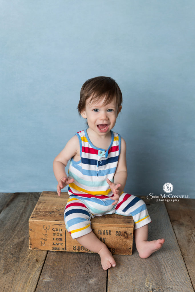one year old in striped romper smiling