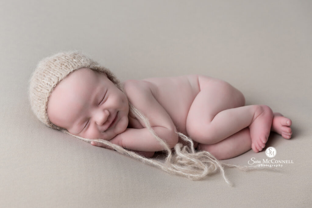 Smiling and sleeping newborn baby laying on their side