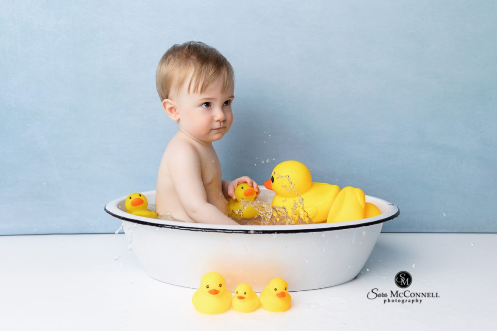 Baby sitting in a bathtub with rubber ducks in a blog post about baby bathtub photography sessions. Ottawa maternity photographer.