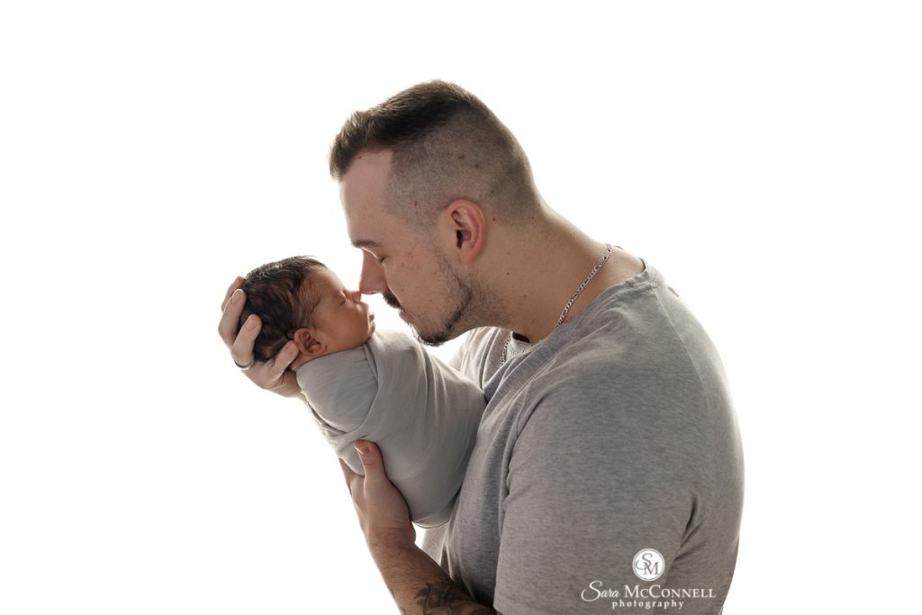 A photo of dad holding his newborn baby in a blog post about styling a newborn session. Newborn photographers ottawa.