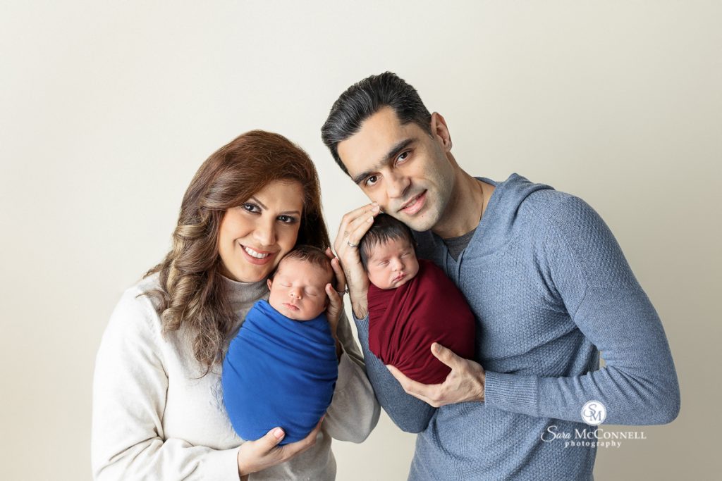 Photo of parents holding their newborn twins in a blog post about what we love about twin newborn sessions. Maternity and newborn photography.