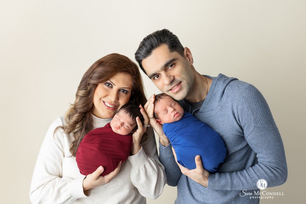 Photo of parents holding their newborn twins in a blog post about what we love about twin newborn sessions. Maternity and newborn photography.