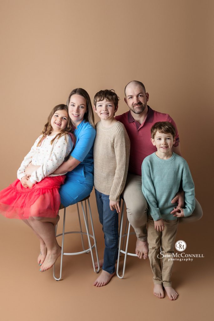 Photo of family of five smiling at the camera in a blog post about Candid versus posed images. Ottawa maternity photographers.
