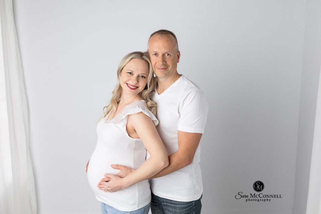 Photo of expectant parents smiling at the camera in a blog post about posing during maternity sessions by an Ottawa maternity photography.