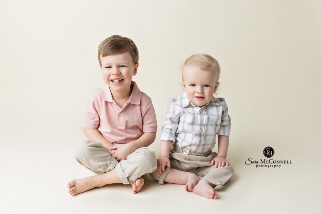 Photo of 2 boys smiling at camera in blog post about ideas for toddler photography sessions. Ottawa maternity photographers.